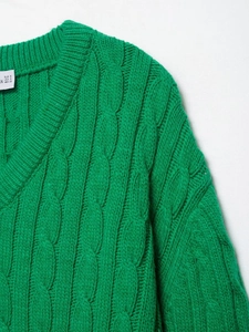 Detail of emerald green cable knit texture and V-neckline on the winter pullover sweater
