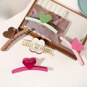 Close-up of heart-shaped hair claw clips in vibrant colors on a wooden tray