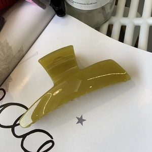 Macro shot of large olive green hair claw clip in glossy resin finish for hair styling