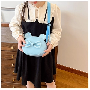 Little girl wearing a light blue round cat-ear crossbody bag with a sequined bow