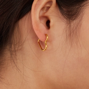 French style heart-shaped gold stainless steel earrings worn by a model in a close-up