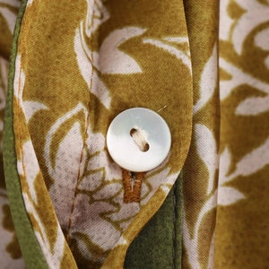 Détail de boutons nacrés blancs et imprimé feuilles vertes sur tissu satiné