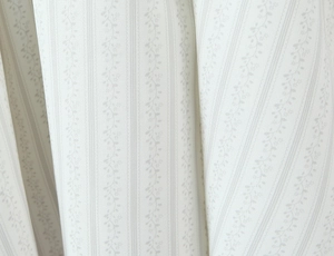 Dettaglio delle strisce verticali e dei motivi floreali sul tessuto bianco crema