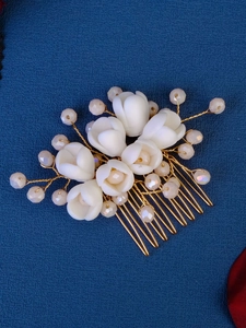 Detail of handcrafted bridal hair comb with ceramic tulips and pearls on blue fabric