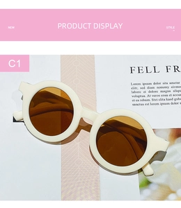Flat lay of cream round frame children sunglasses on a stylish magazine background