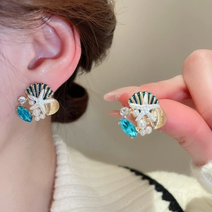 Detail of starfish and shell earrings with blue rhinestones and pearls on model