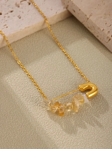 Gros plan d'un pendentif épingle de sûreté doré avec pierres naturelles et perles