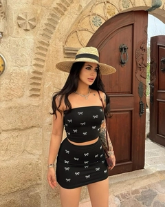 Detail shot of black two-piece set featuring silver bow patterns and a mini skirt
