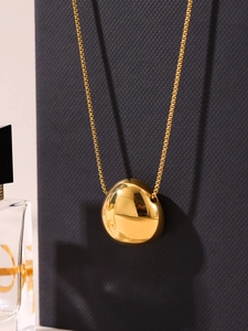 Macro shot of 18K gold plated irregular bean pendant on a fine box chain necklace