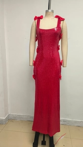 Detail of red sequined dress showing satin bow accents and shimmering fabric texture