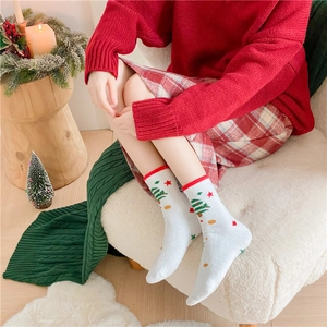 Gros plan de chaussettes de Noël en polaire blanche avec sapin vert et étoiles rouges