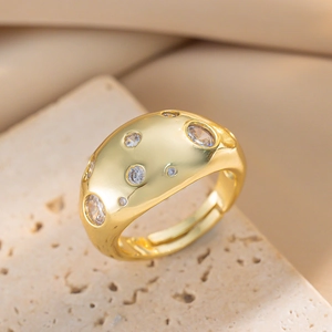 Gold plated zircon ring with chunky hammered texture displayed on a stone pedestal