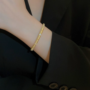 Macro shot of gold-plated brushed metal bangle with cubic zirconia on a model