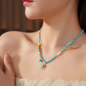 Détail du collier de perles turquoise avec pendentif soleil et perles blanches