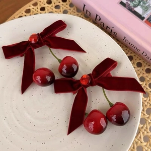Close-up of red velvet cherry hair clips with faux gems on an elegant decorative tray