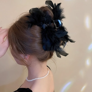 Detail view of a black fluffy feather hair claw clip worn on hair with elegant styling
