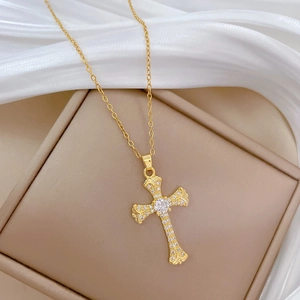 Close-up of gold-plated cross necklace with shimmering diamonds on white silk fabric