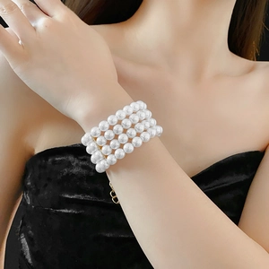Gros plan d'un bracelet à cinq rangées de perles blanches avec un fermoir doré élégant