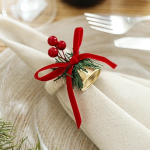 Christmas napkin ring with red velvet ribbon, golden bell, and pine cones on table