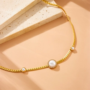 Gold flat snake chain necklace featuring three round white pearls and crystal accents