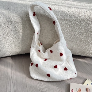 Dettaglio del tessuto della borsa tote in peluche bianca con ricami a cuore rosso