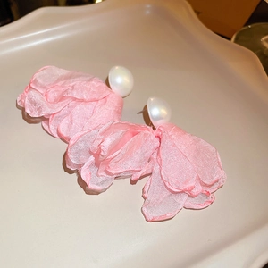 Detailed view of pink tulle flower earrings with white pearls on a decorative tray