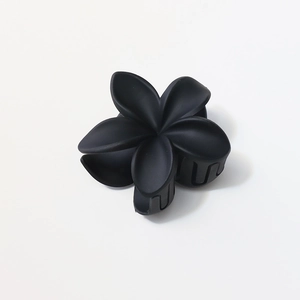 Macro shot of 8cm matte black plumeria flower claw clip with smooth resin finish