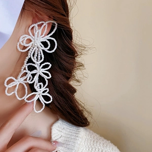 Close-up of white beaded flower tassel earrings worn by a model for an elegant look
