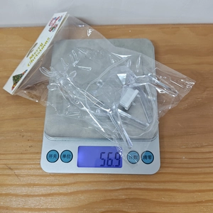 Weight measurement of clear acrylic leaping reindeer ornament in festive packaging