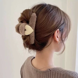 Detail of plush brown shark clip with cream heart worn on a woman's hair
