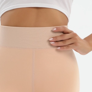 Detail of high waisted ribbed waistband on beige thermal leggings with seamless texture
