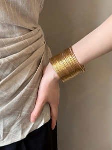 Close-up of bohemian style layered golden metal wire wrap cuff bracelet on model wrist