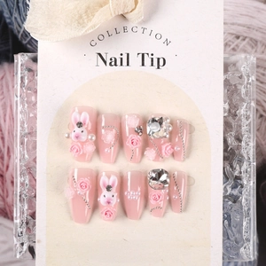 Close-up of pink press-on nails with 3D bunny, roses and pearls on card packaging