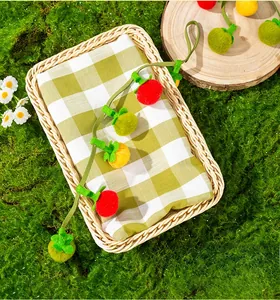 Detailed view of plush persimmon cat toys with bells on a woven tray with moss background