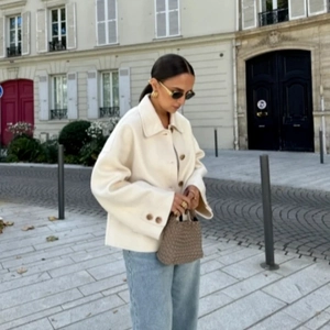 Street style shot of a cream-colored wool coat featuring lapels and large button details