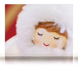 Close-up of plush Christmas angel doll face featuring a closed-eye smiling expression
