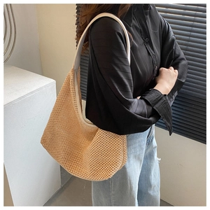 Detail of a beige straw woven shoulder bag with a white strap shown on a model