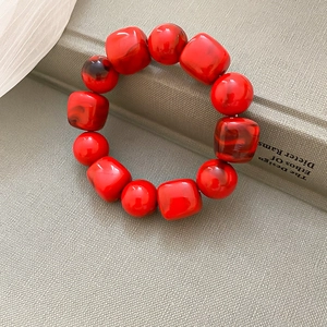 Détail d'un bracelet en acrylique marbré rouge avec perles rondes et carrées