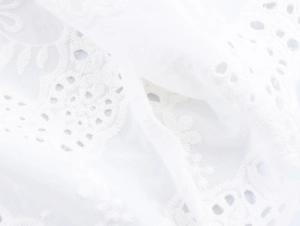 Detail der weißen hohlen Blumenstickerei und feinen Spitzenstofftextur am Kleid