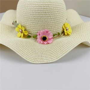Detailed macro view of beige woven straw hat featuring colorful floral band and wavy brim
