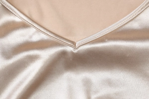 Gros plan sur l'encolure en V profonde d'une robe en satin champagne aux finitions soignées