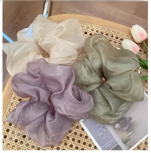 Detailed texture of large organza hair scrunchies in cream, purple, and peacock green