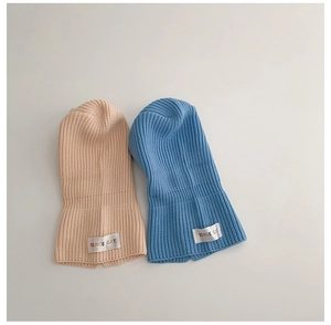 Detail of knitted baby balaclava hat with colorful Pierce Cat label in blue and beige