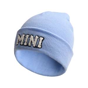 Close-up of light blue knitted beanie featuring textured MINI letter towel embroidery