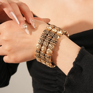 Detail of vintage gold-tone wide cuff bracelet with rhinestones and scroll patterns