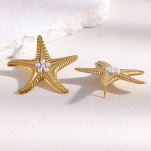 Detailed view of 18K gold-plated starfish stud earrings with pearls on textured stone