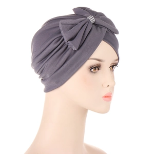 Dark grey turban cap with a large bow and silver rhinestone knot shown on a model