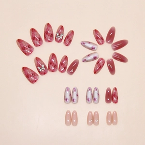 Dettaglio di unghie finte con decorazioni a rosa, fiocchi metallici e strass