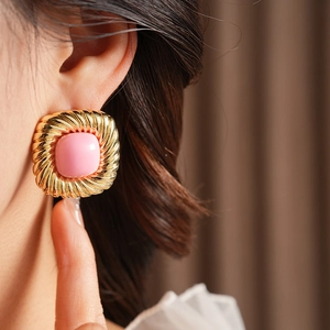 Details von Vintage-Goldohrringen in Quadratform mit rosa Edelstein am Modell