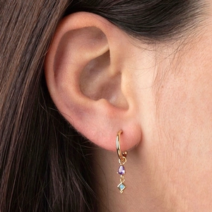 Elegant gold drop earrings with purple teardrop and blue cubic zirconia on model